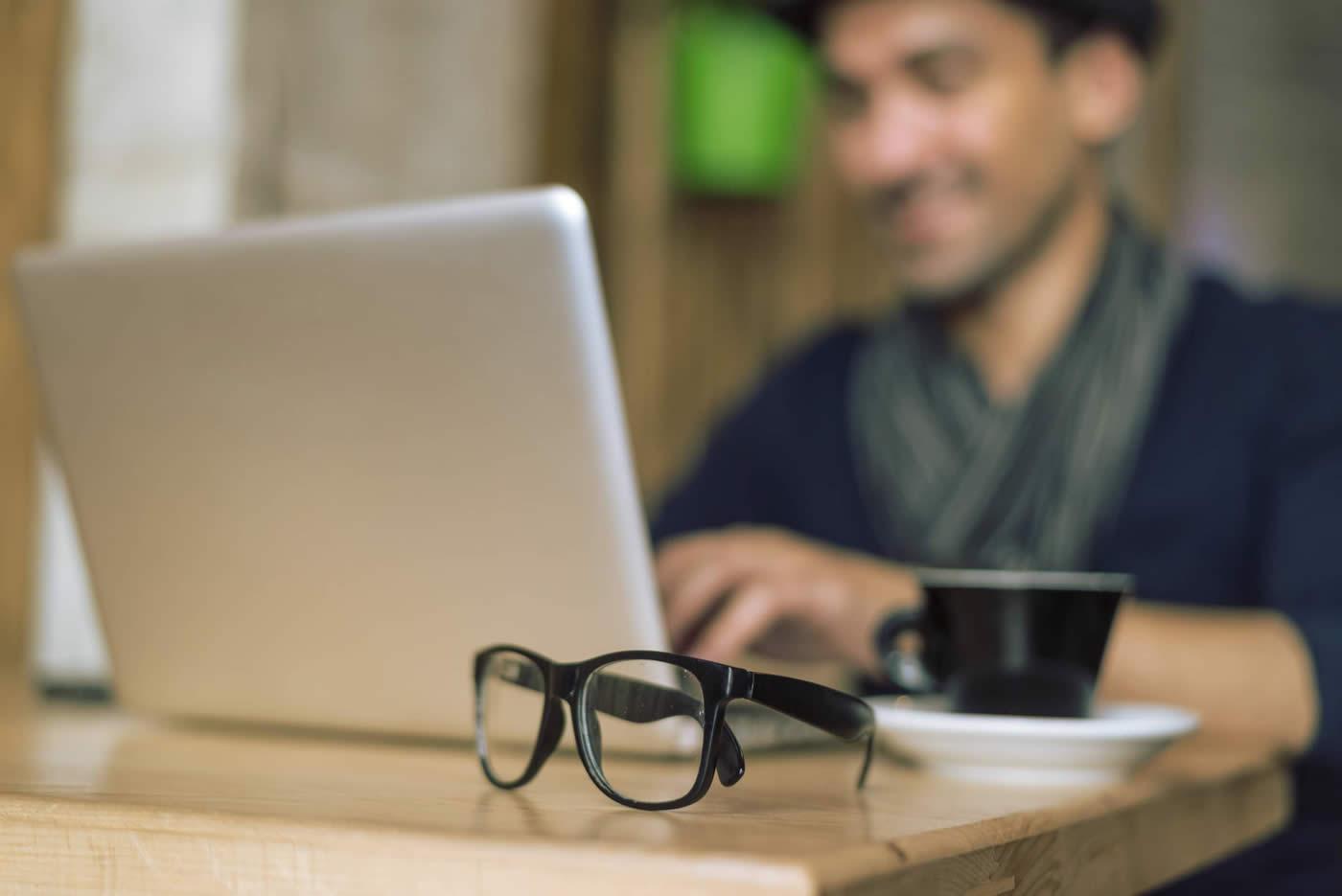 Man working on laptop with hot drink