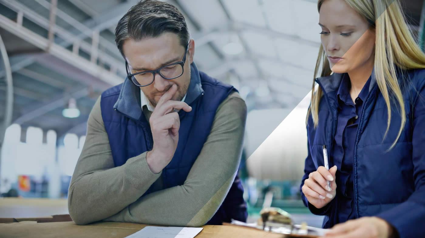 Two workers in warehouse studying paperwork