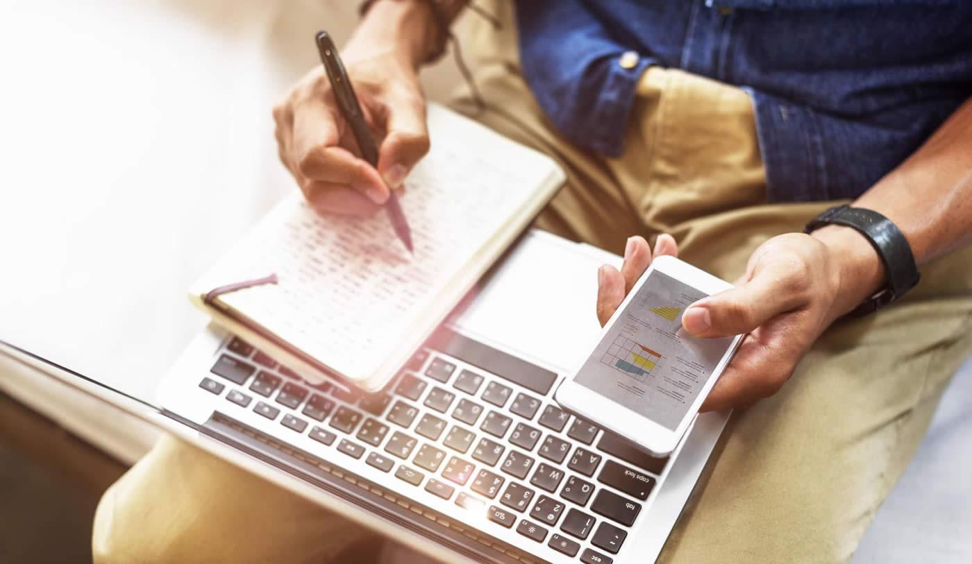 Person working on laptop with notepad