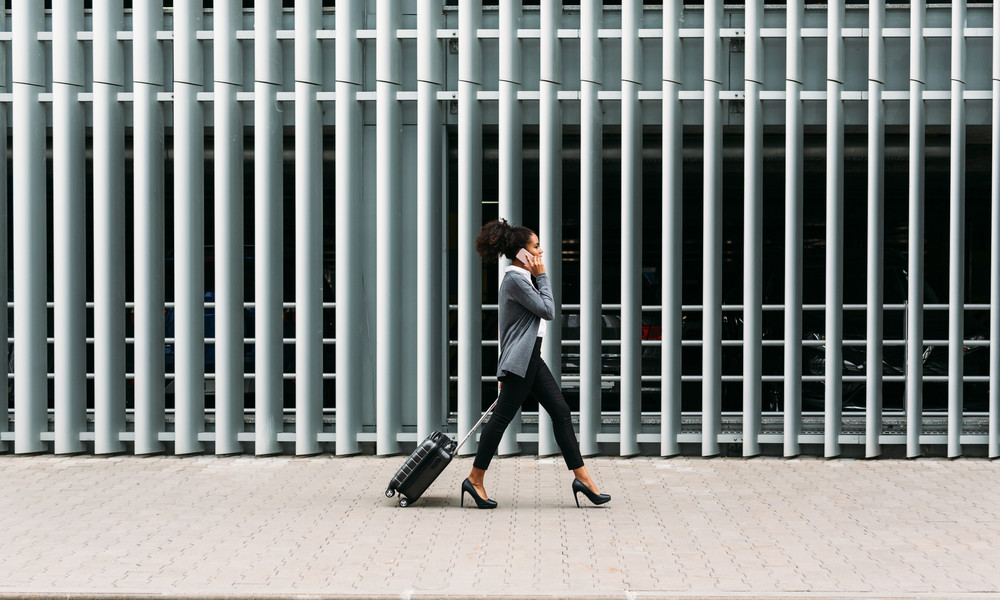 Side view of young businesswoman walking with suitcase