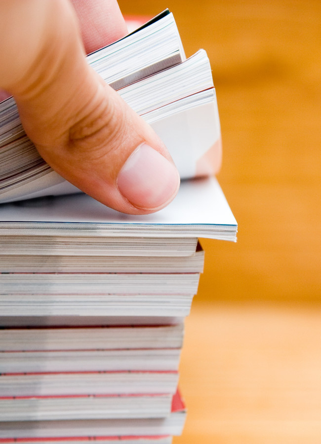hand browsing through stack of magazines