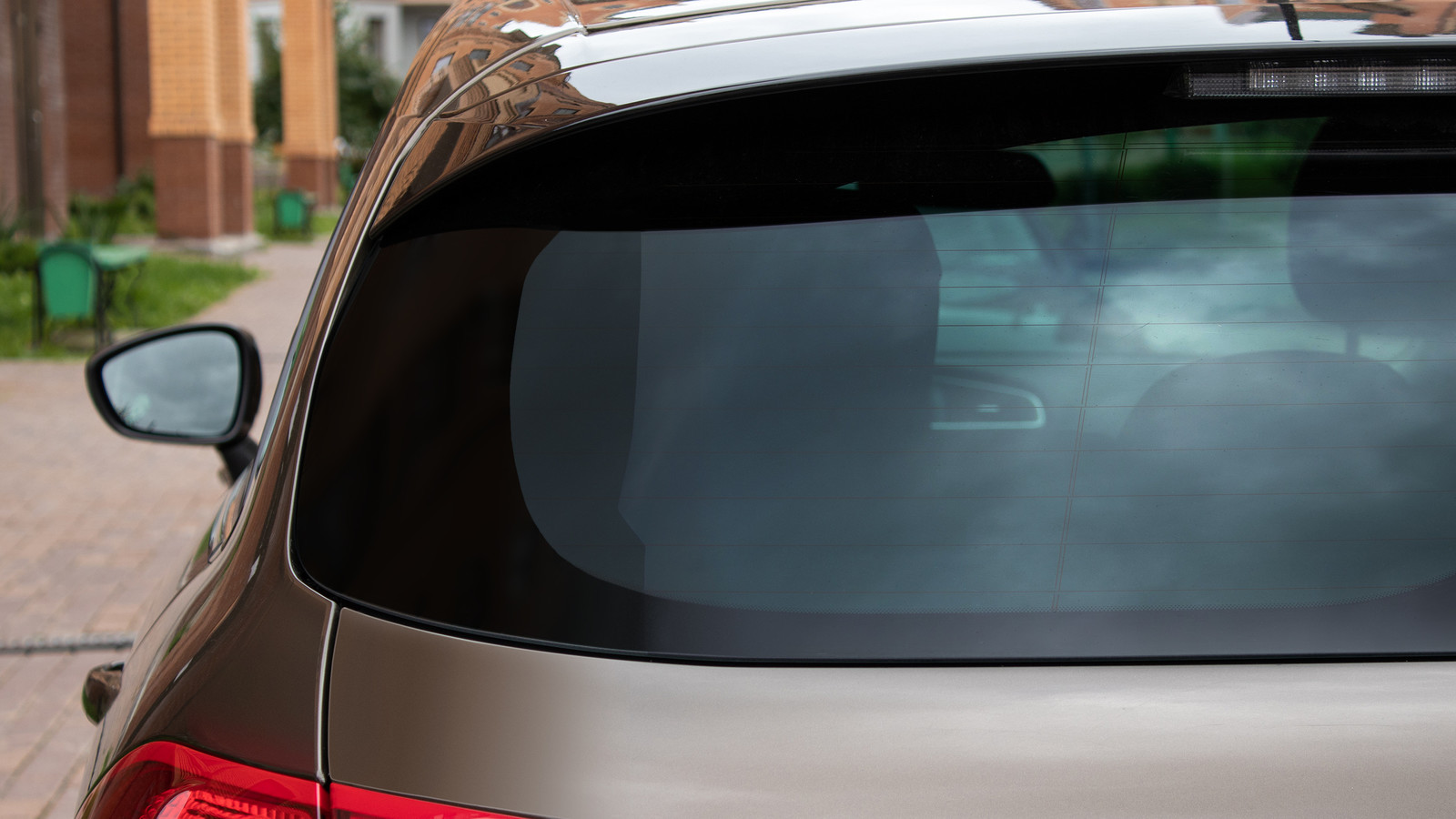 Back window of a car parked on the street in summer sunny day, rear view.